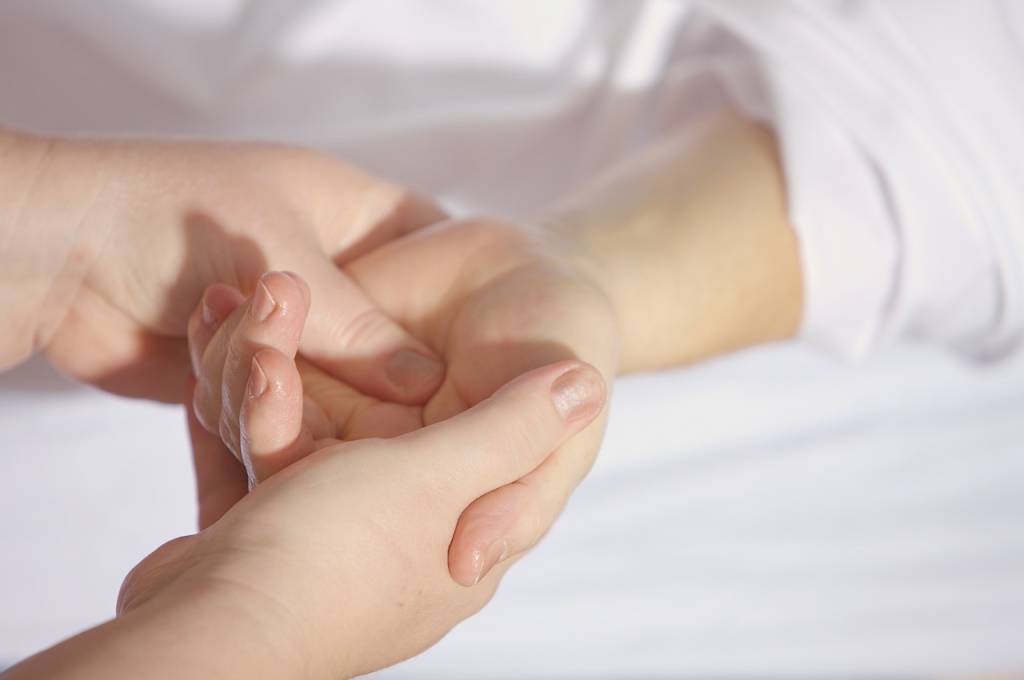 Hands providing gentle massage therapy to a senior's hand, emphasizing comfort and care in a soothing environment.